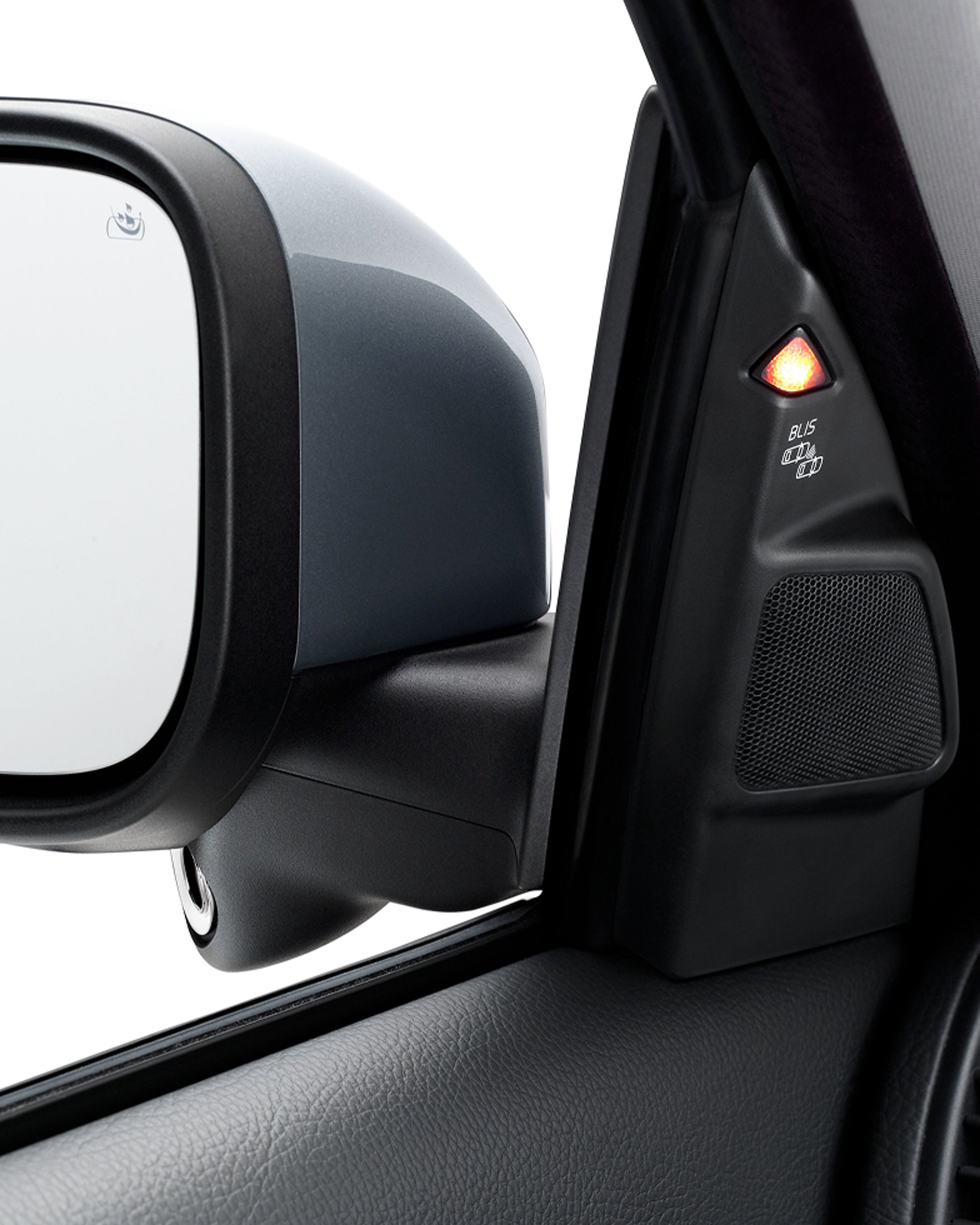 汽车侧视镜和门柱的特写,带有亮起的橙色 BLIS(盲点信息系统)警示灯。