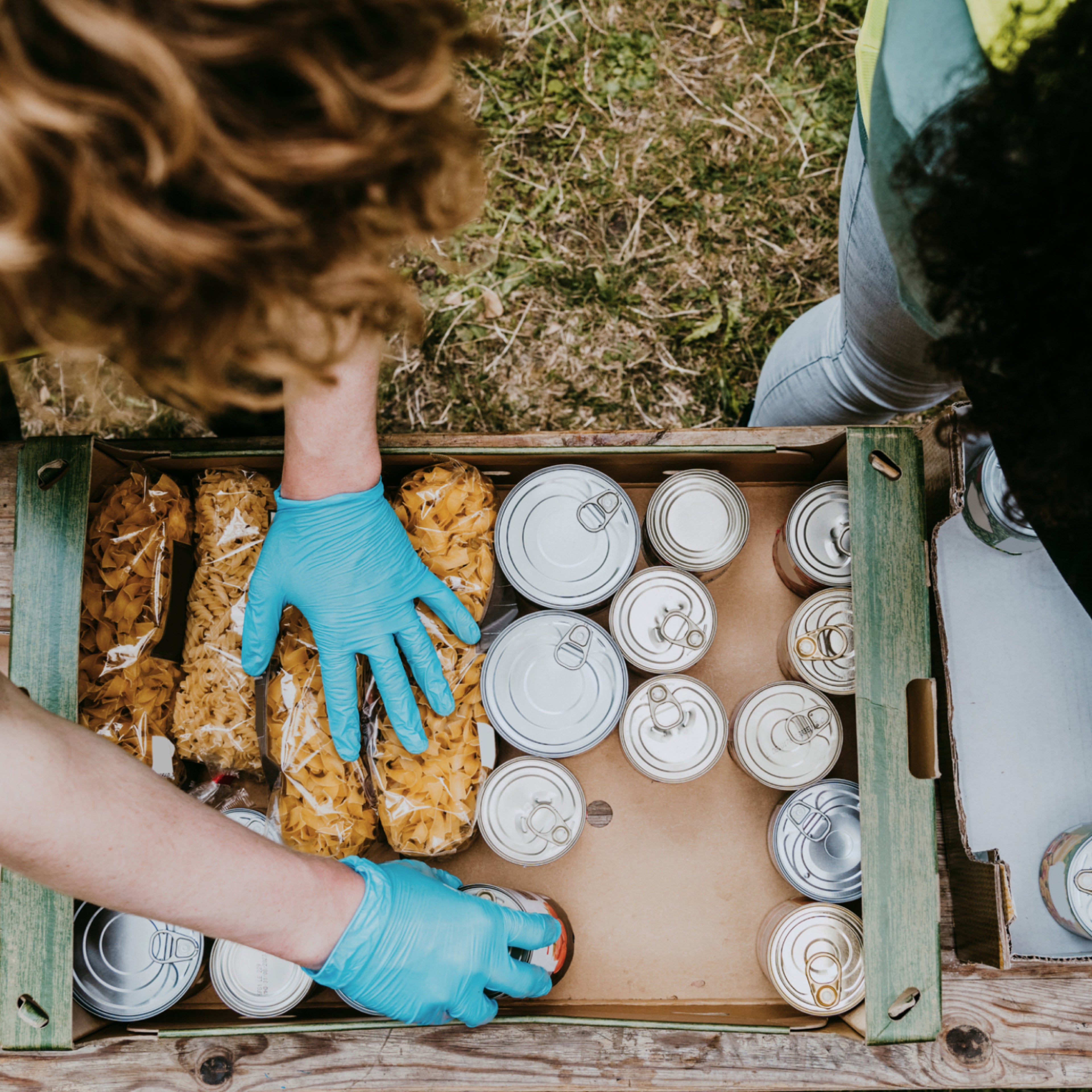 一个人为紧急救援将干面条和食品罐头放入盒子中的俯视图。