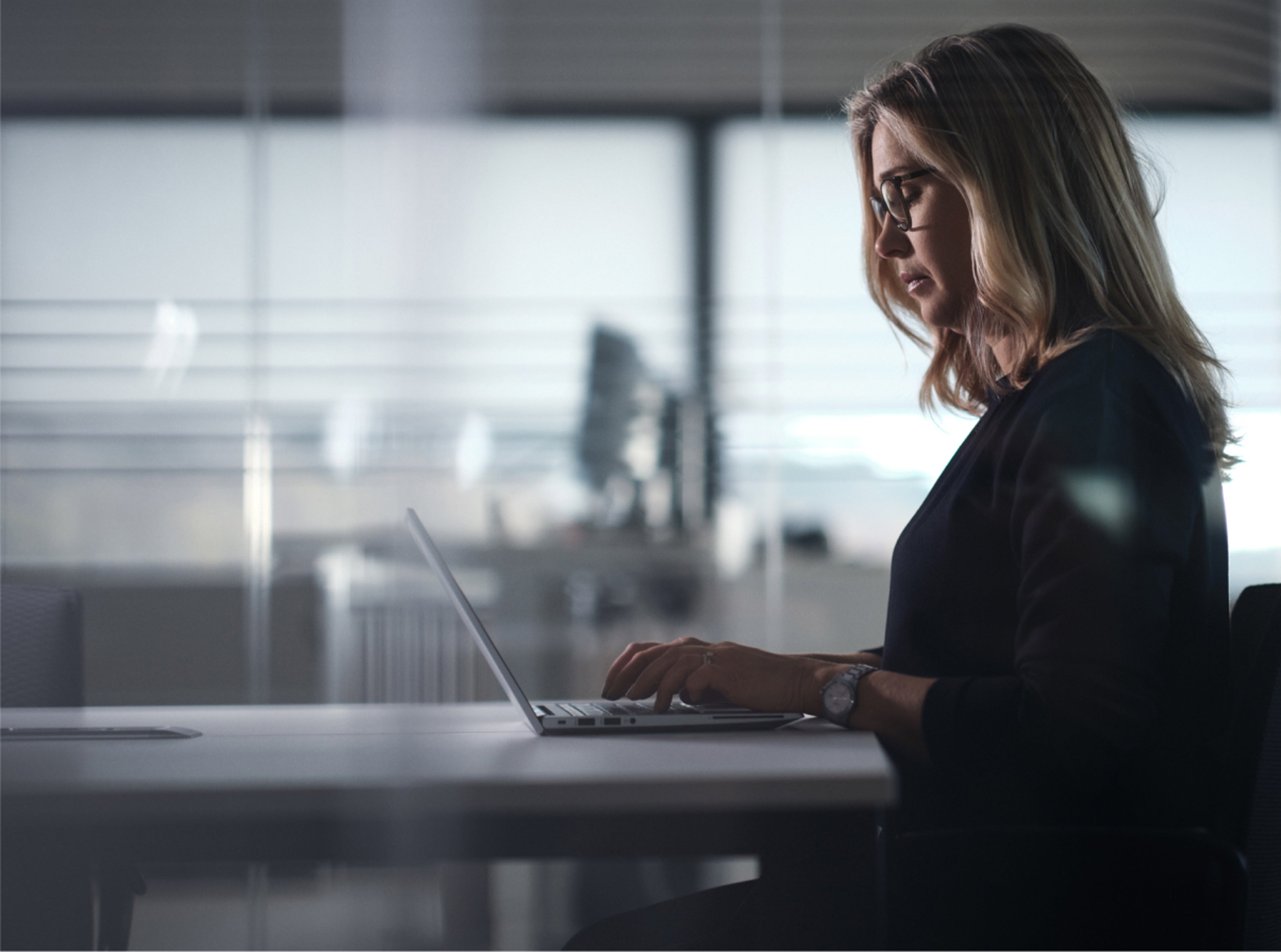 一名女士在使用笔记本电脑工作的侧影。