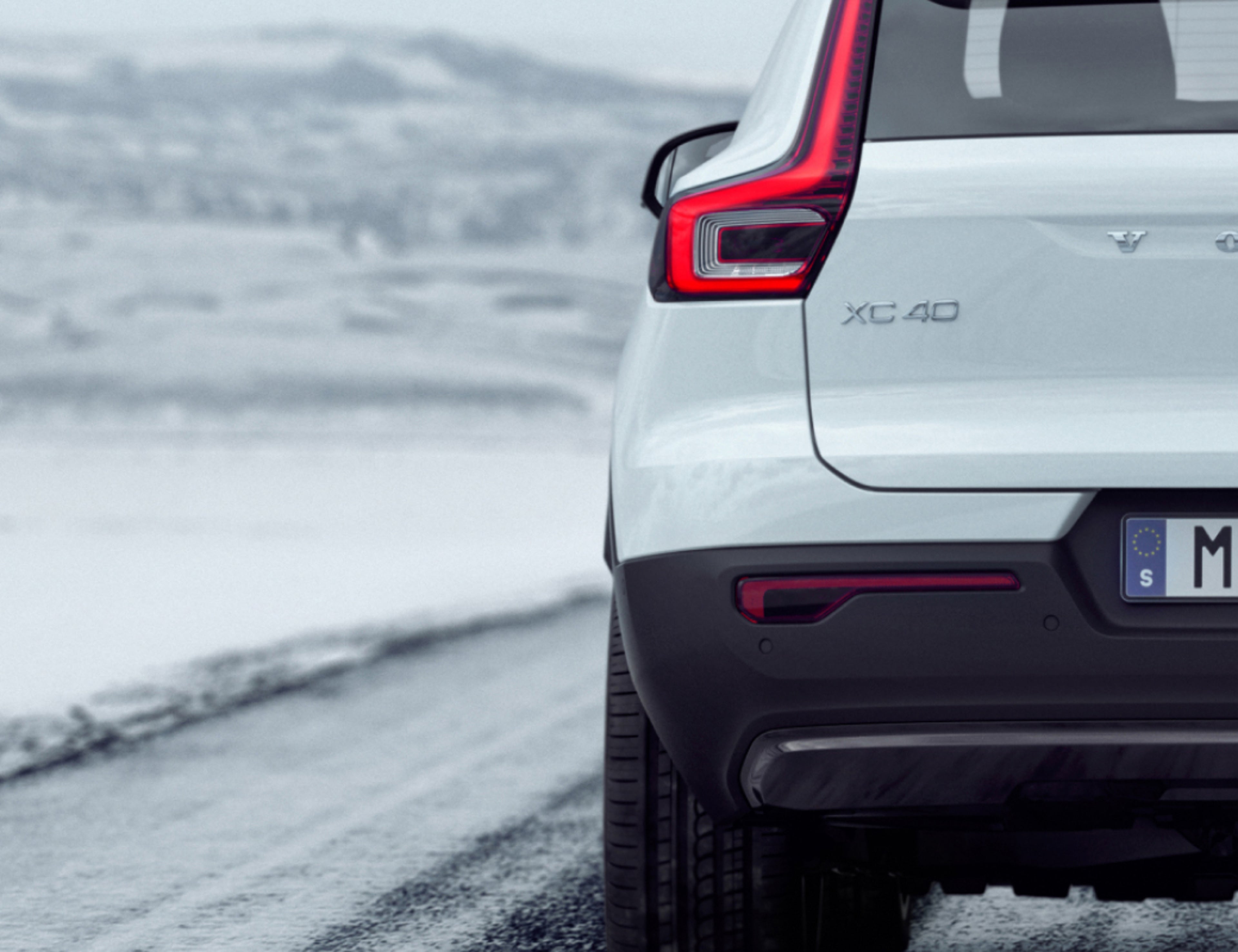 白色 VOLVO XC40 行驶在结冰路面上的局部后视图。