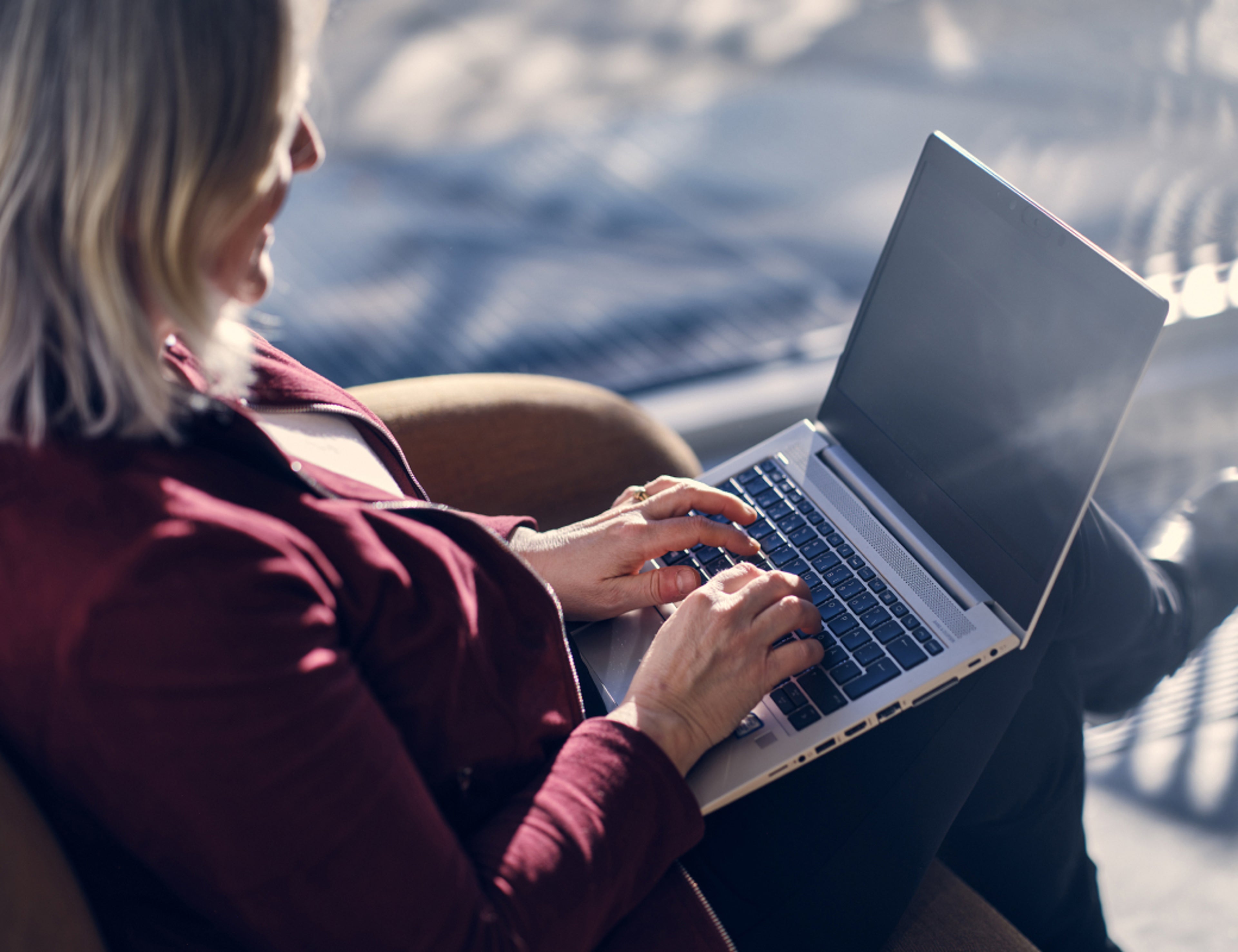 一名女士坐在沙发上使用笔记本电脑的俯视图。