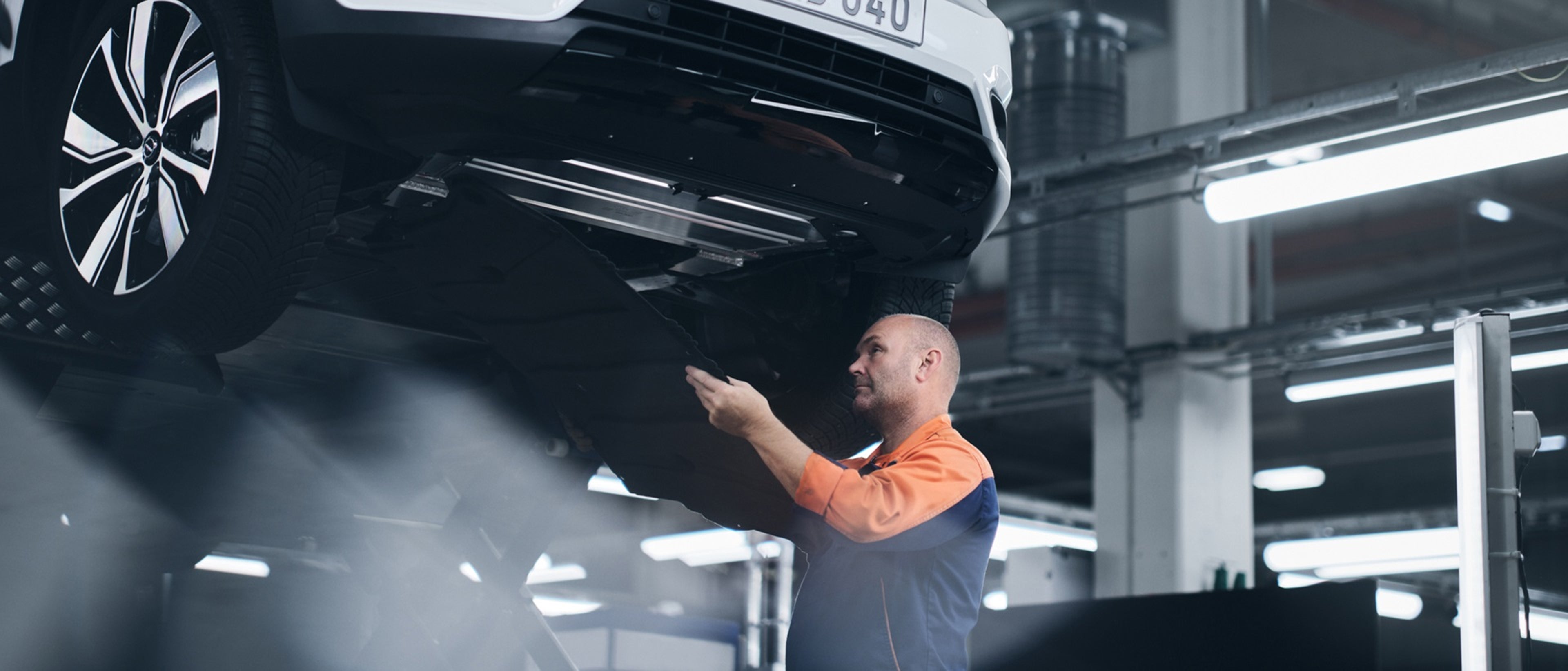 一名男子在被吊起的汽车下工作。