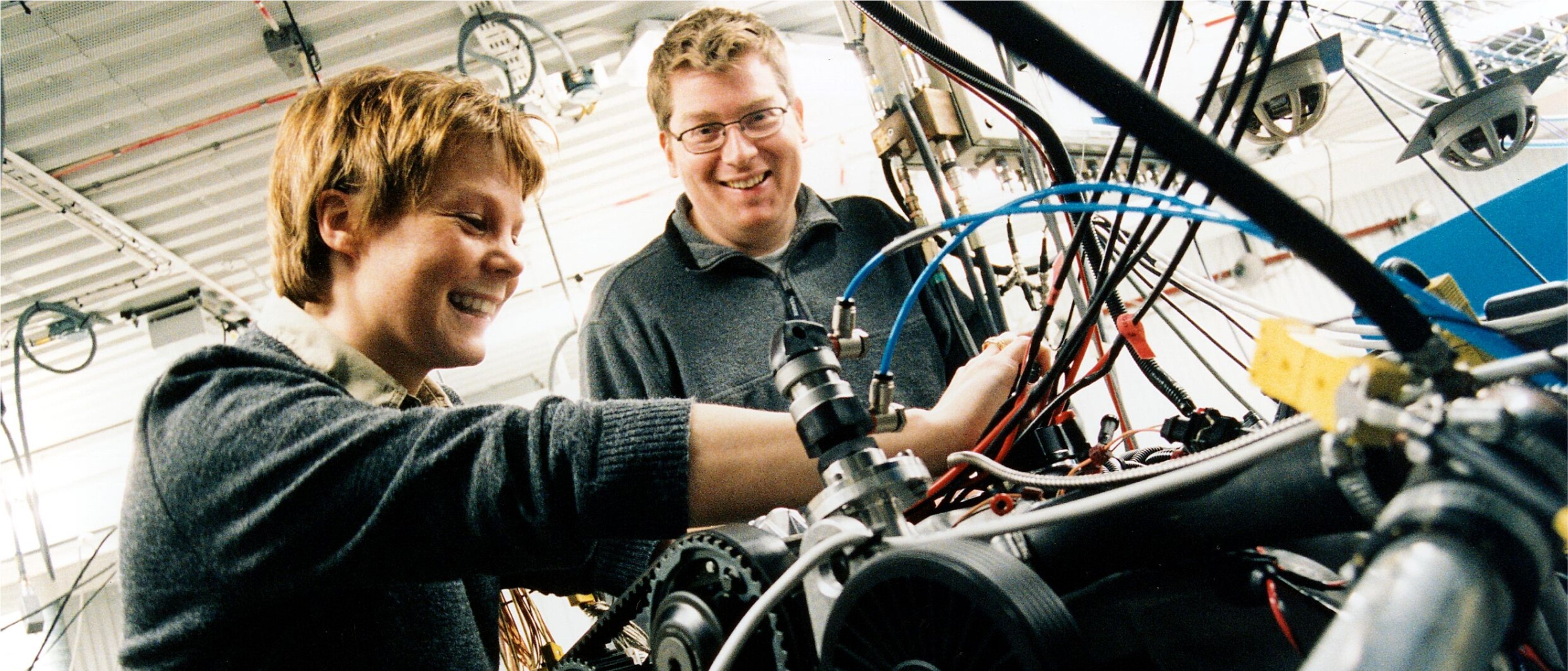 沃尔沃汽车制造工厂内一男一女边微笑边操作着电机。