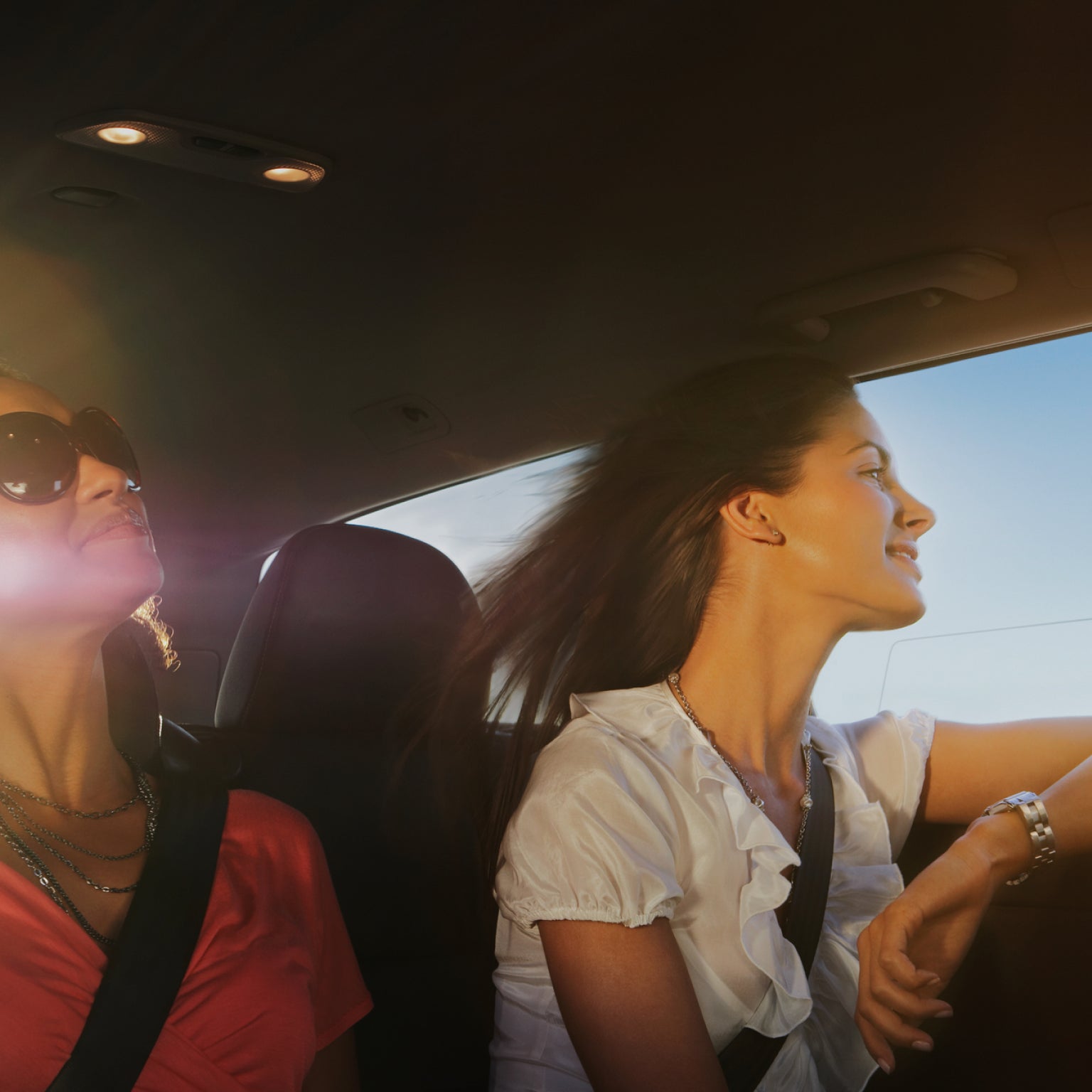 一名女子坐在乘客位上,透过车窗向外望去,风吹拂着她的秀发。