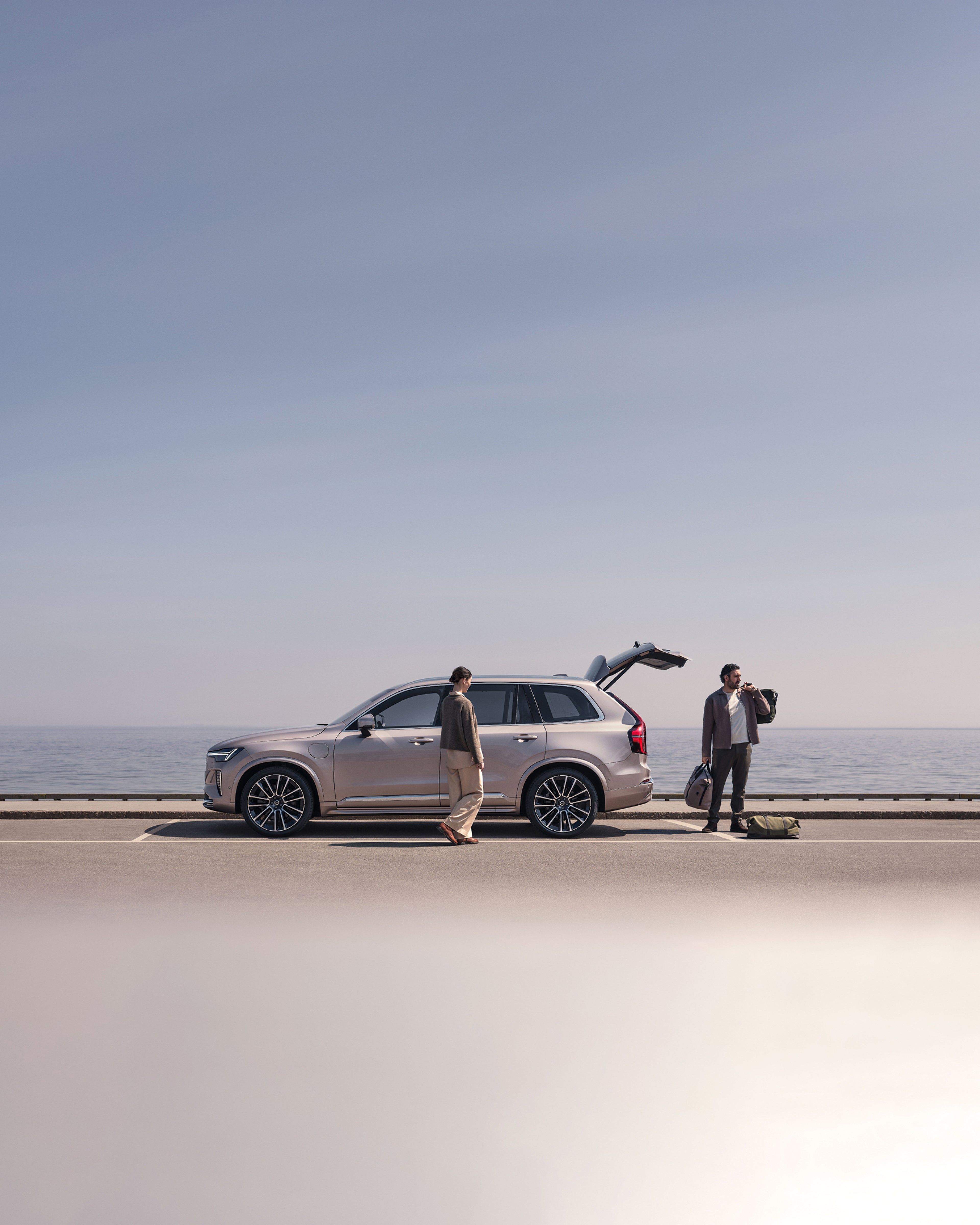 一对男女在水边为他们的沃尔沃 XC90 装载物品。