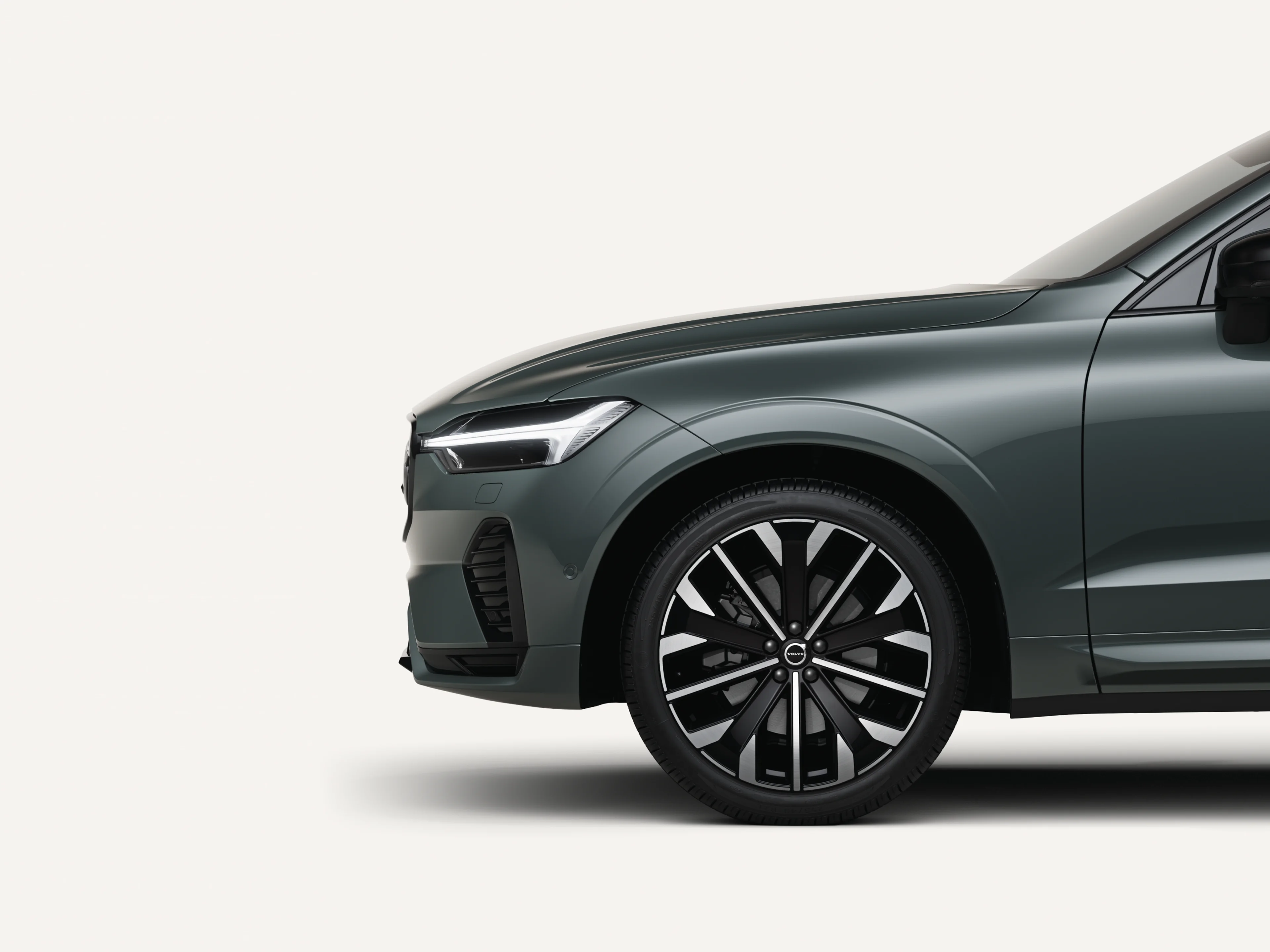 沃尔沃全新 XC60 轻度混合动力中型 SUV 停在白色工作室内的二分之一正视图。