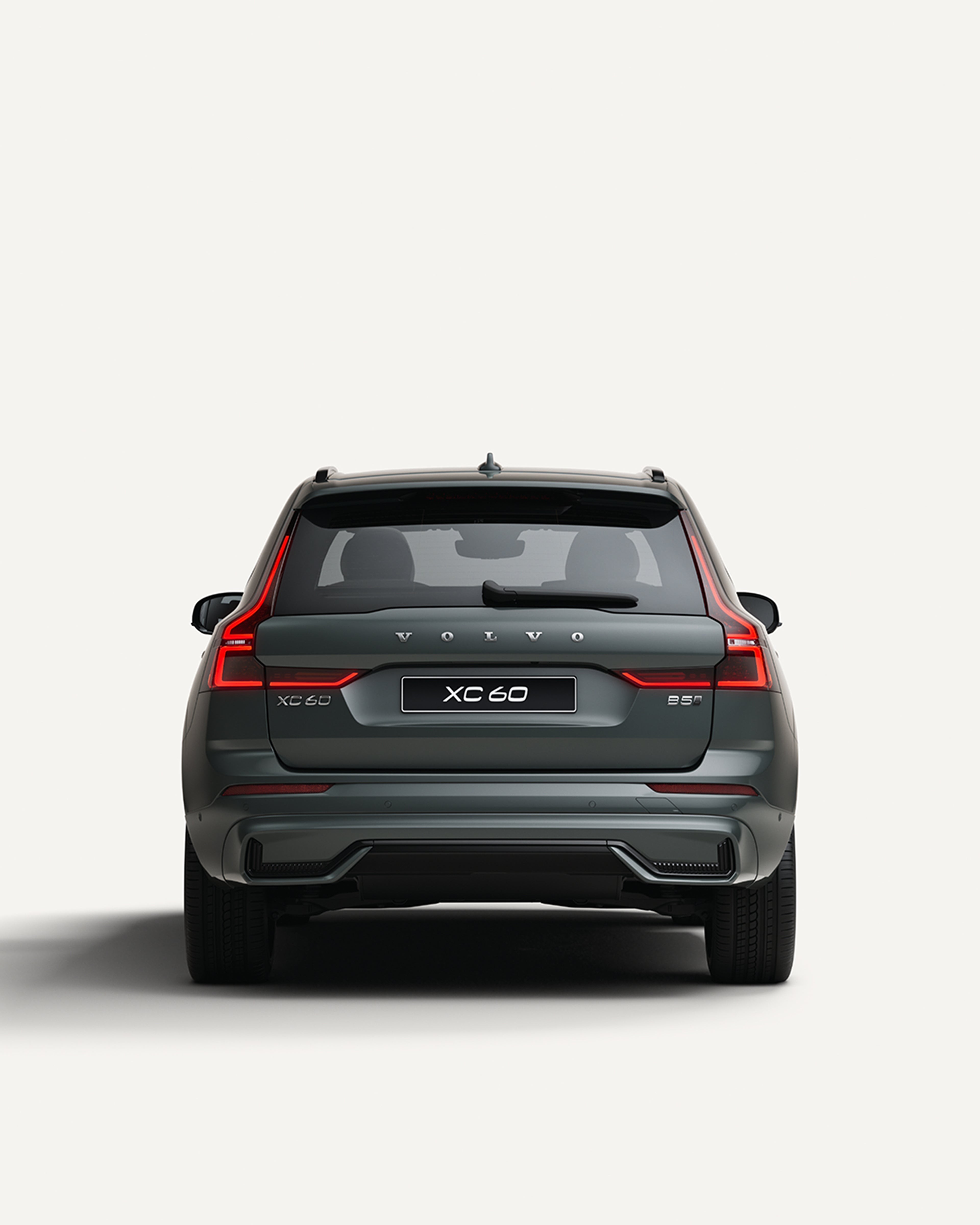 沃尔沃全新 XC60 轻度混合动力中型 SUV 停在白色工作室内的后视图。