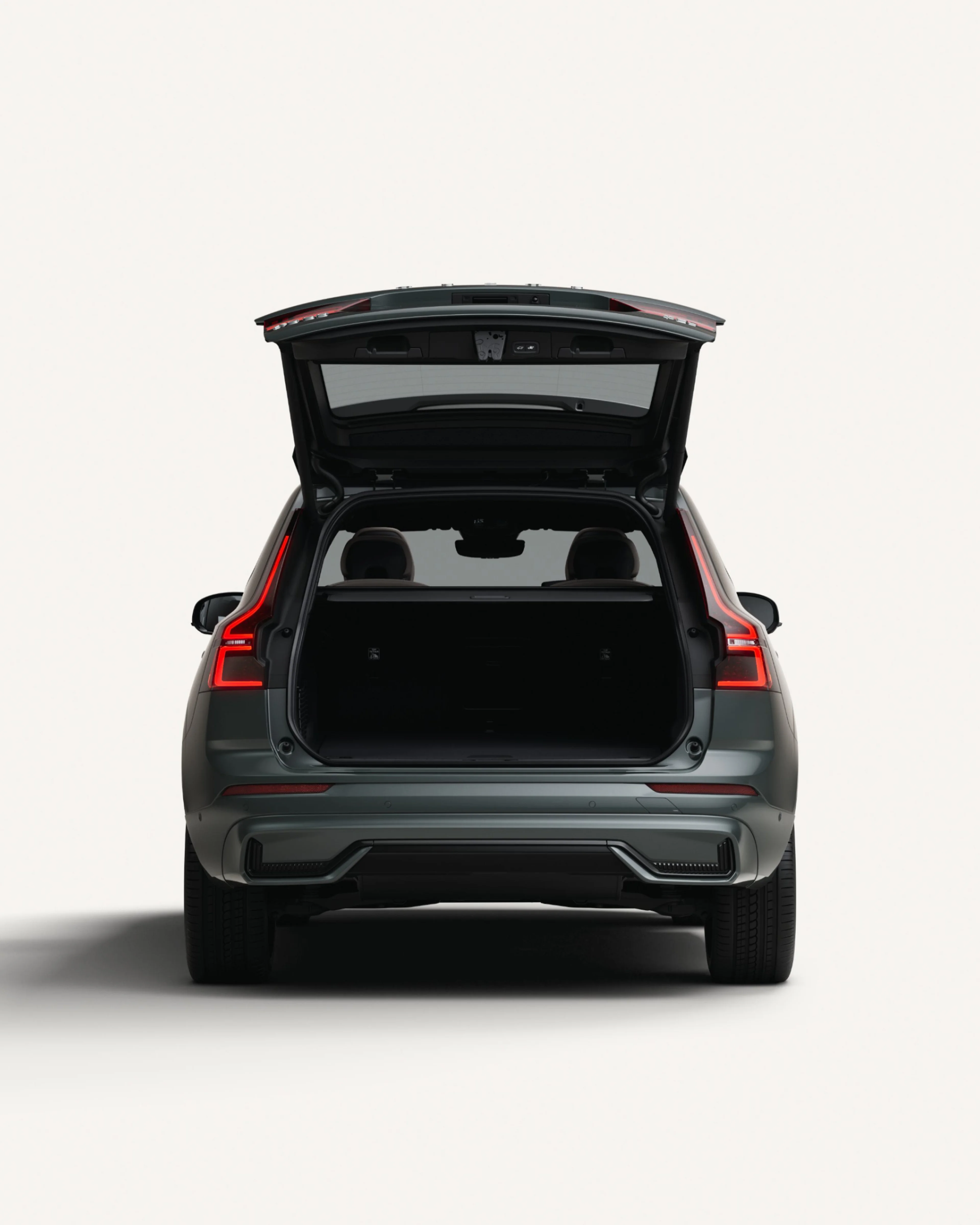 沃尔沃全新 XC60 插电式混合动力中型 SUV 停在白色工作室内,后备箱敞开着。