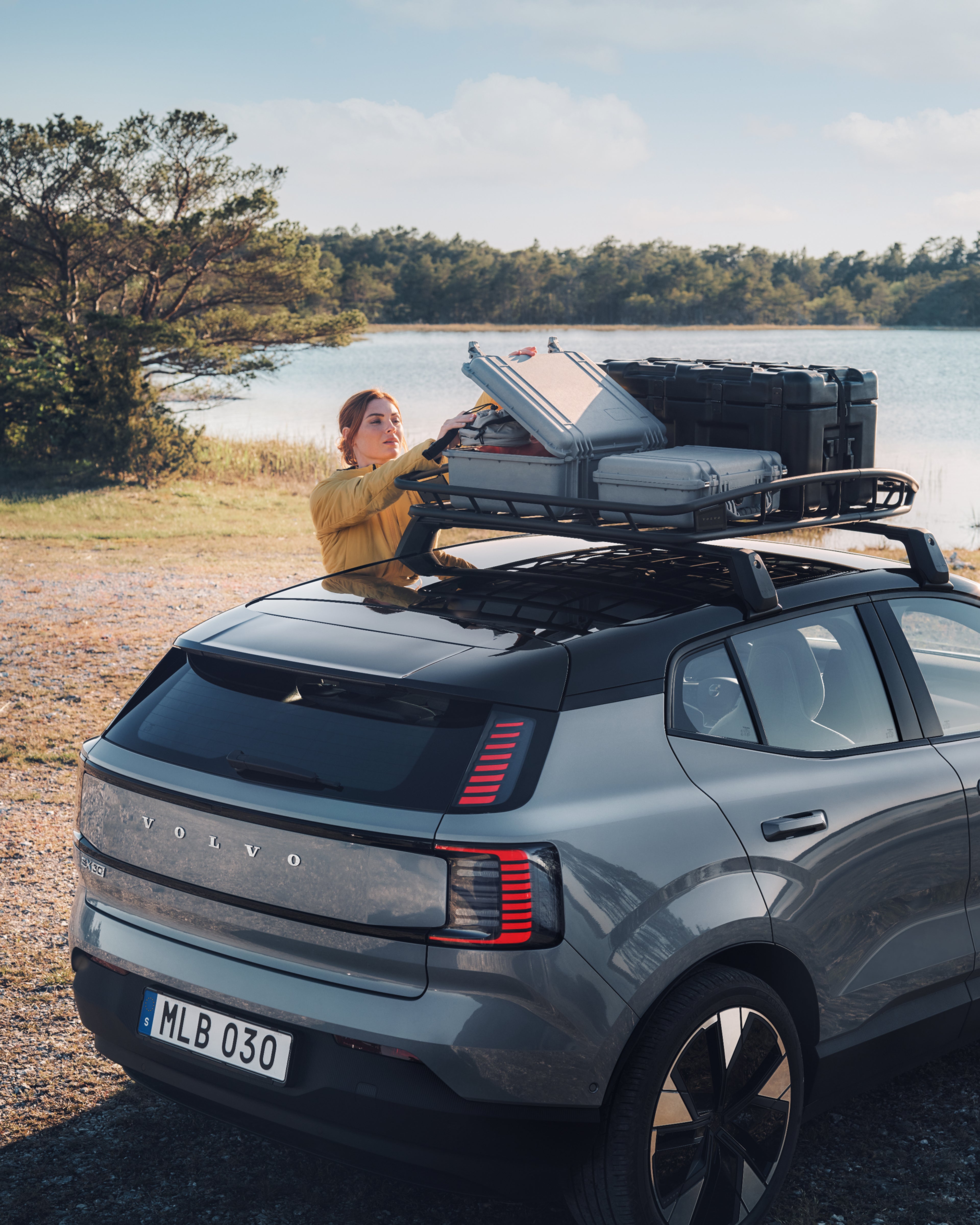 EX30 车尾斜视图,其中一位女士伸手去够车顶行李框。