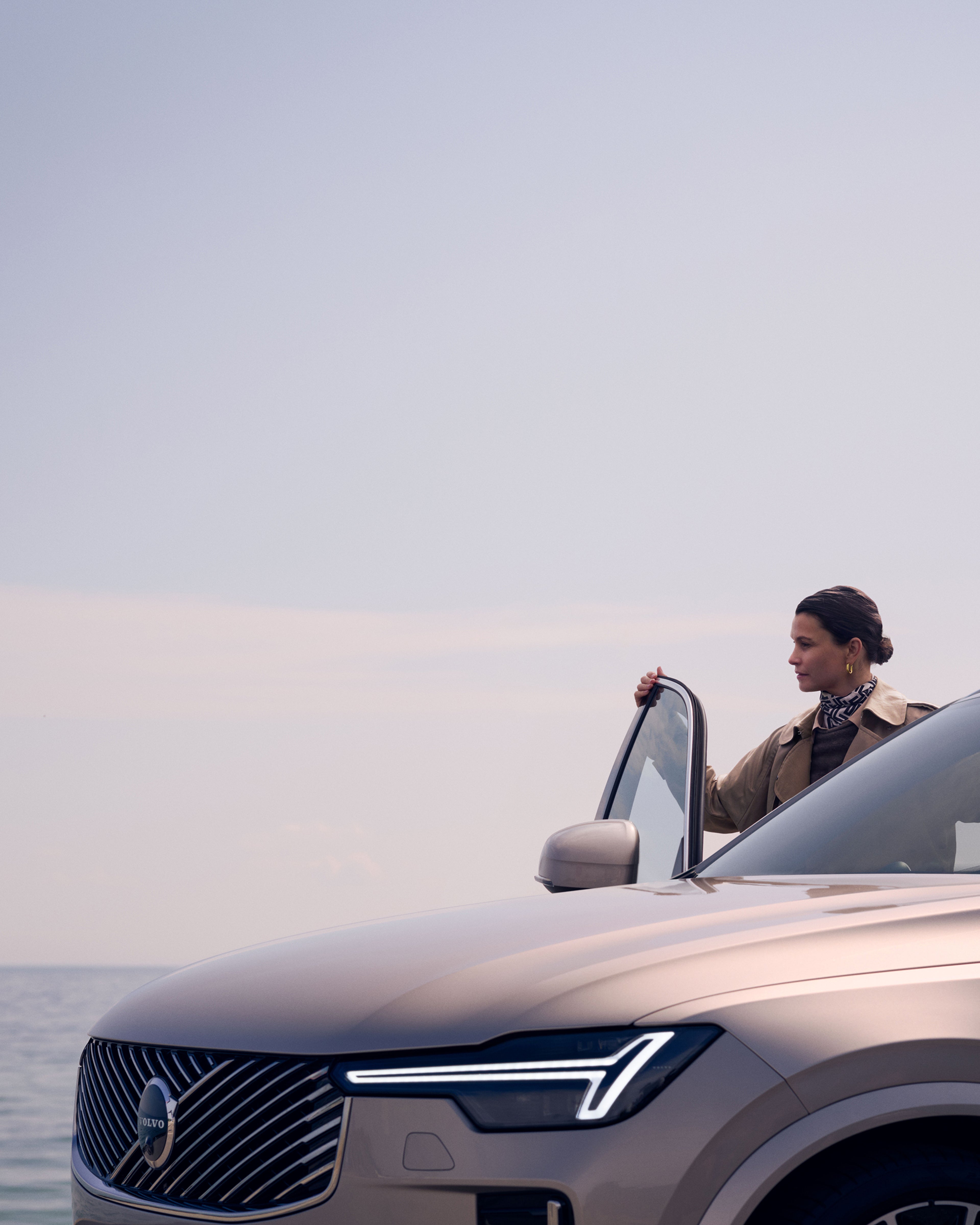 沃尔沃 XC90 正面特写,一位女士站在打开的乘客侧车门内