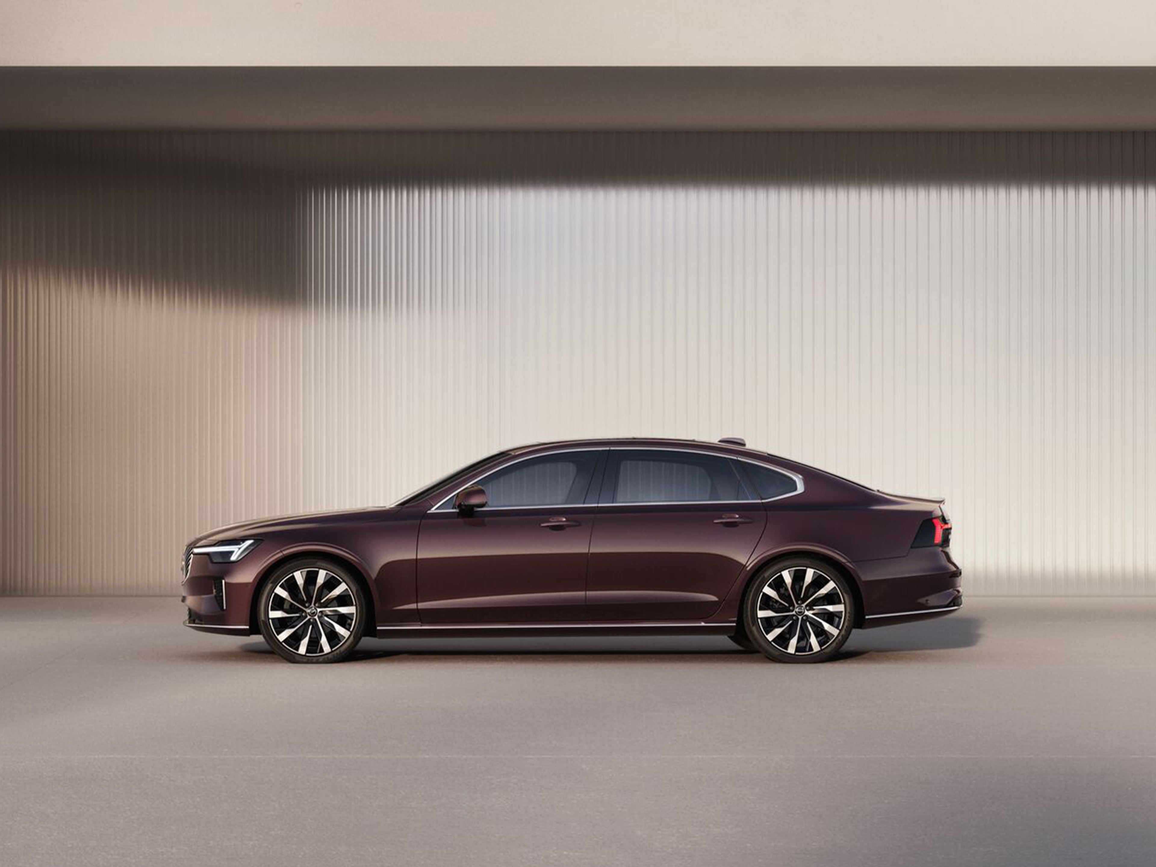 一辆黑色沃尔沃 S90 靠墙停着。