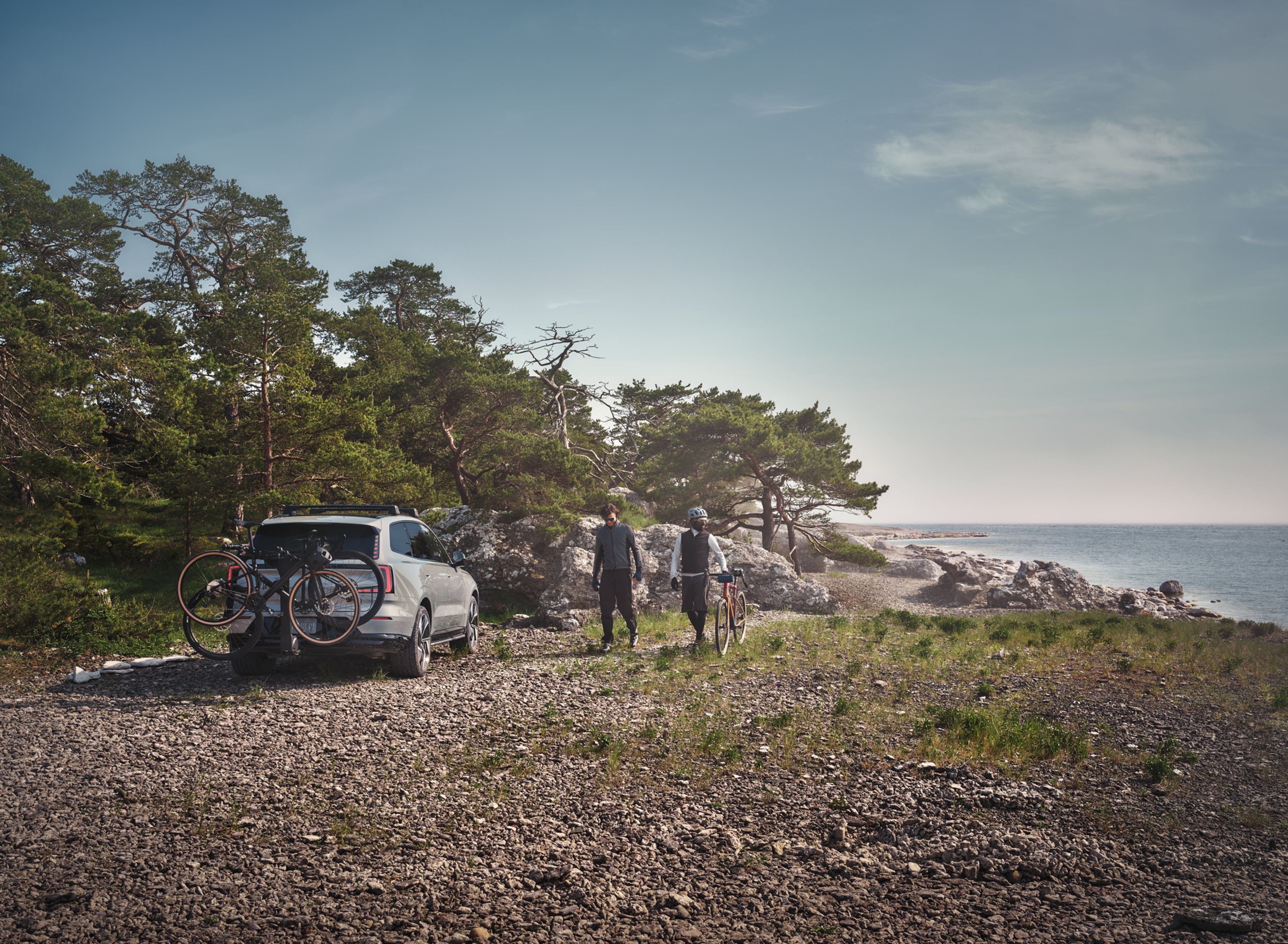 两个朋友走回一辆停着的沃尔沃车,车的拖杆上固定着载满自行车的车架。