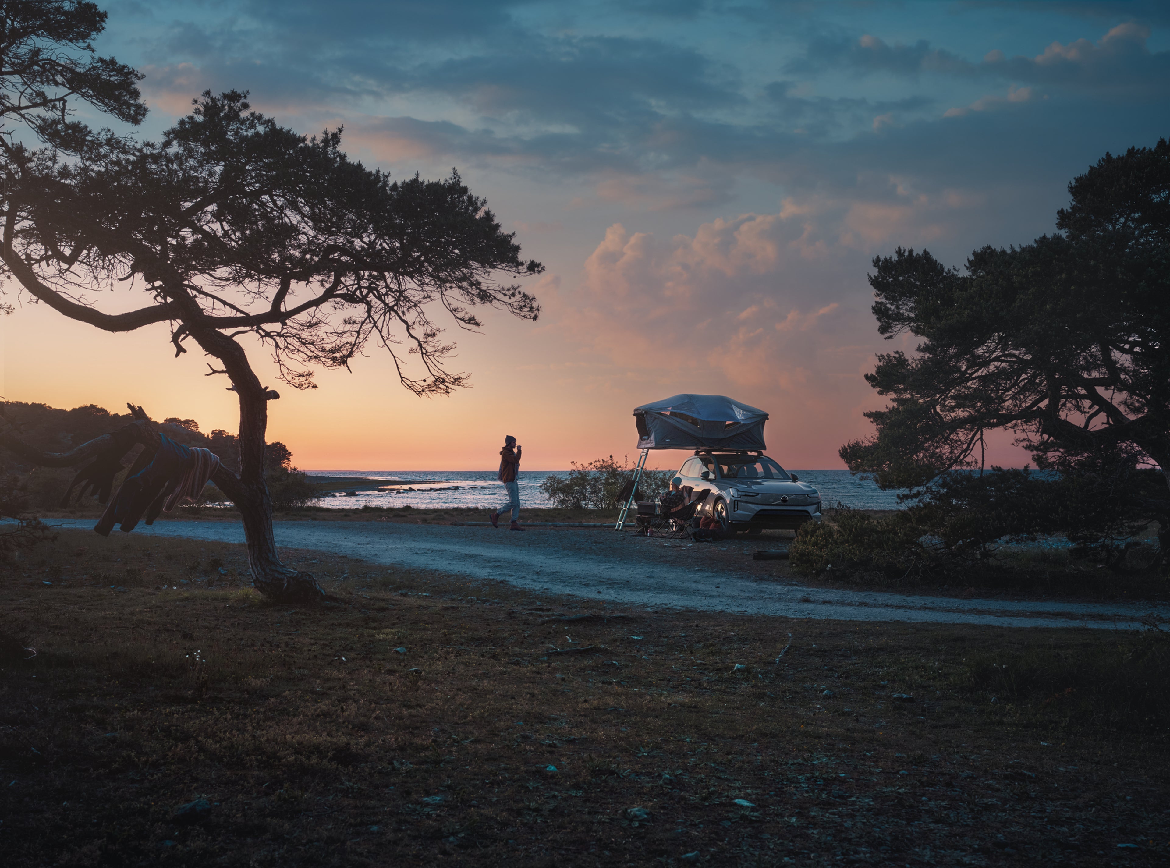 人们在大自然中露营,车顶帐篷牢固地安装在停放的沃尔沃汽车的车顶上。