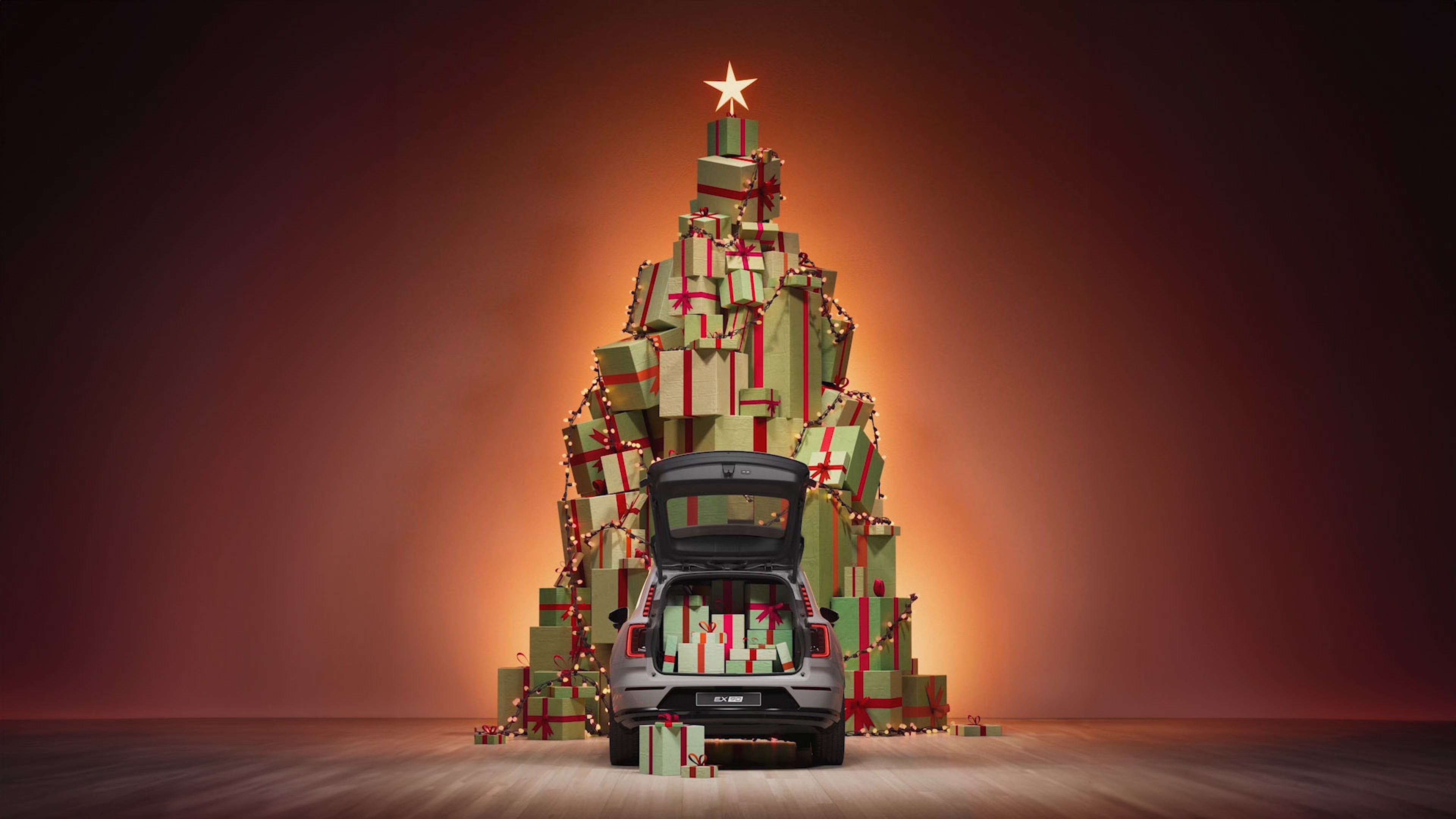 照片:圣诞树前停着一辆后备厢装满礼物的灰色沃尔沃 EX90。