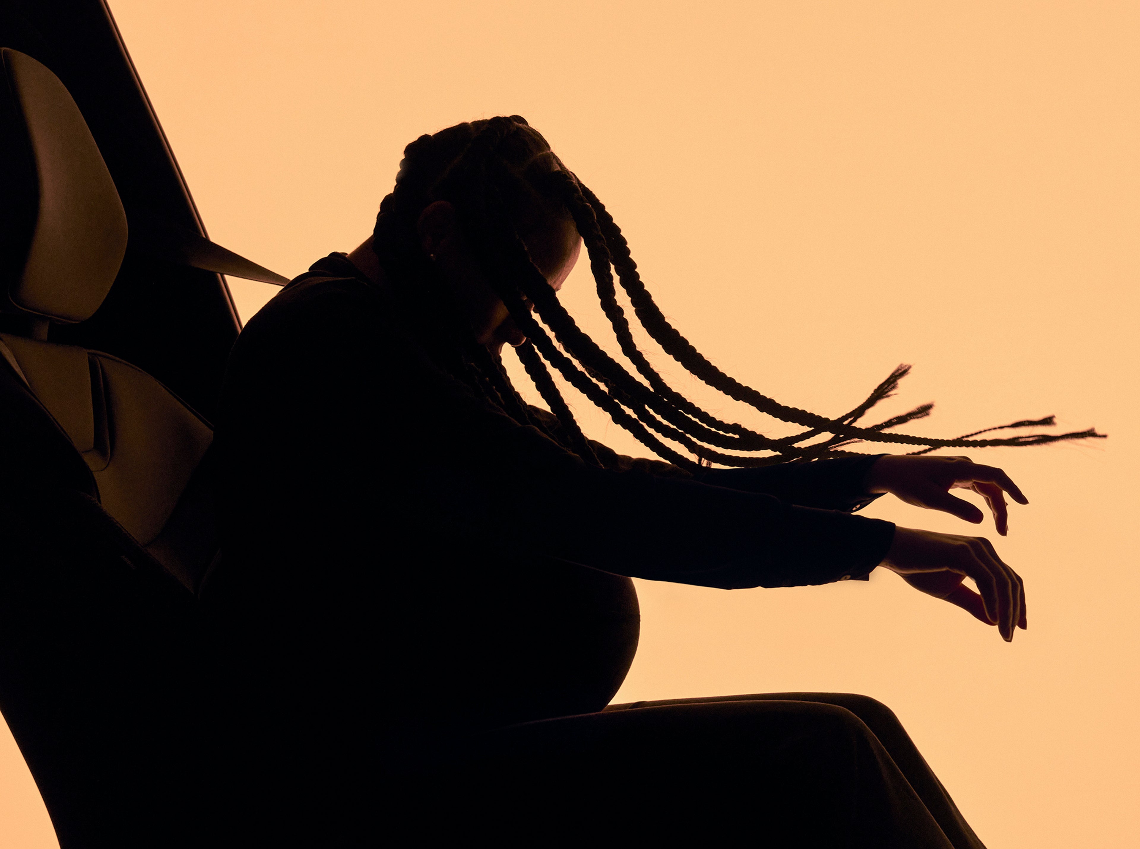 一位扎着辫子的孕妇在车内经历模拟碰撞运动的剪影,展示了沃尔沃汽车为保护不同体型的用户而开发的多重自适应安全带技术。