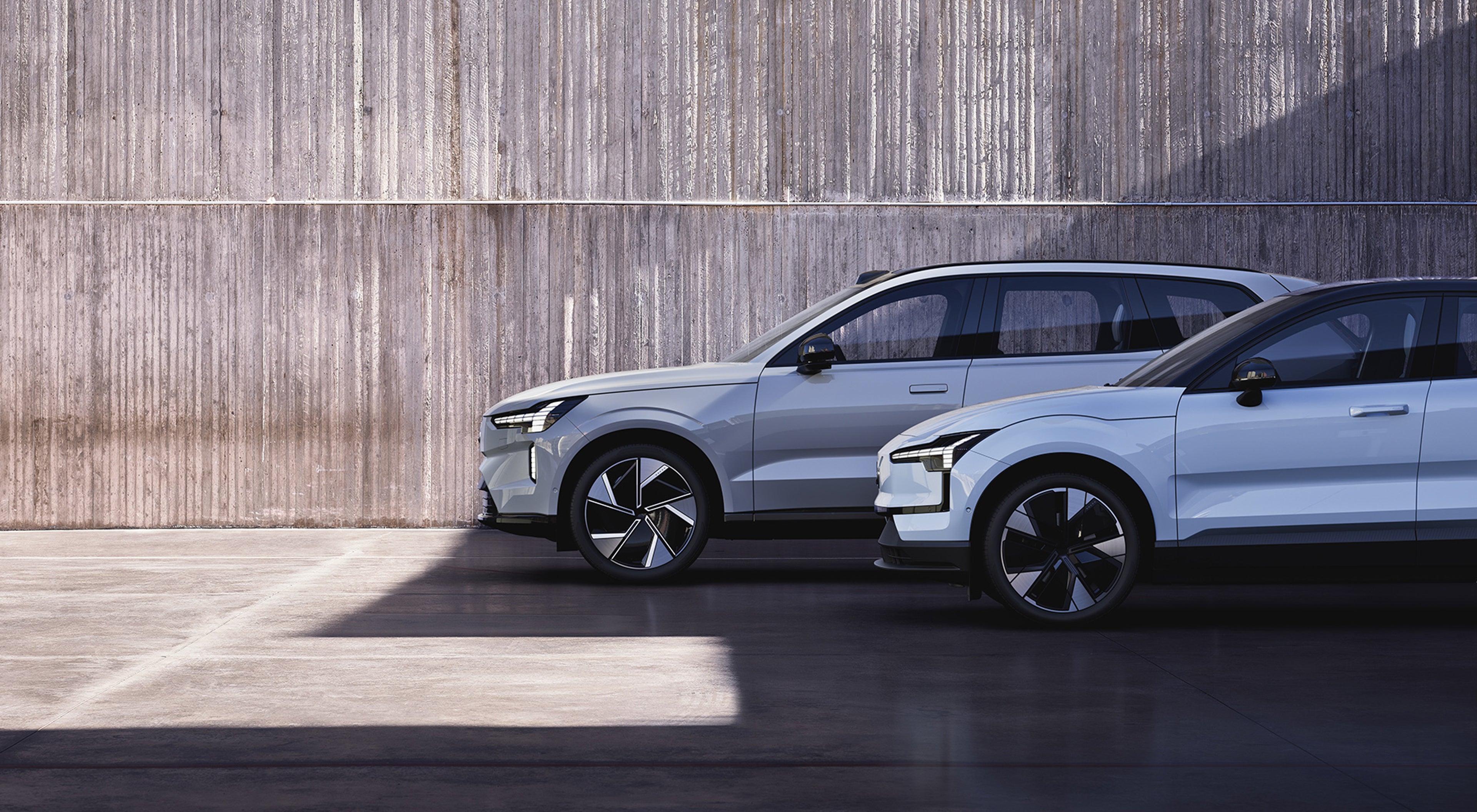 几辆沃尔沃纯电动车停在一堵混凝土墙旁。