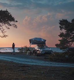 人们在大自然中露营,屋顶帐篷牢固地固定在停放的Volvo顶上。