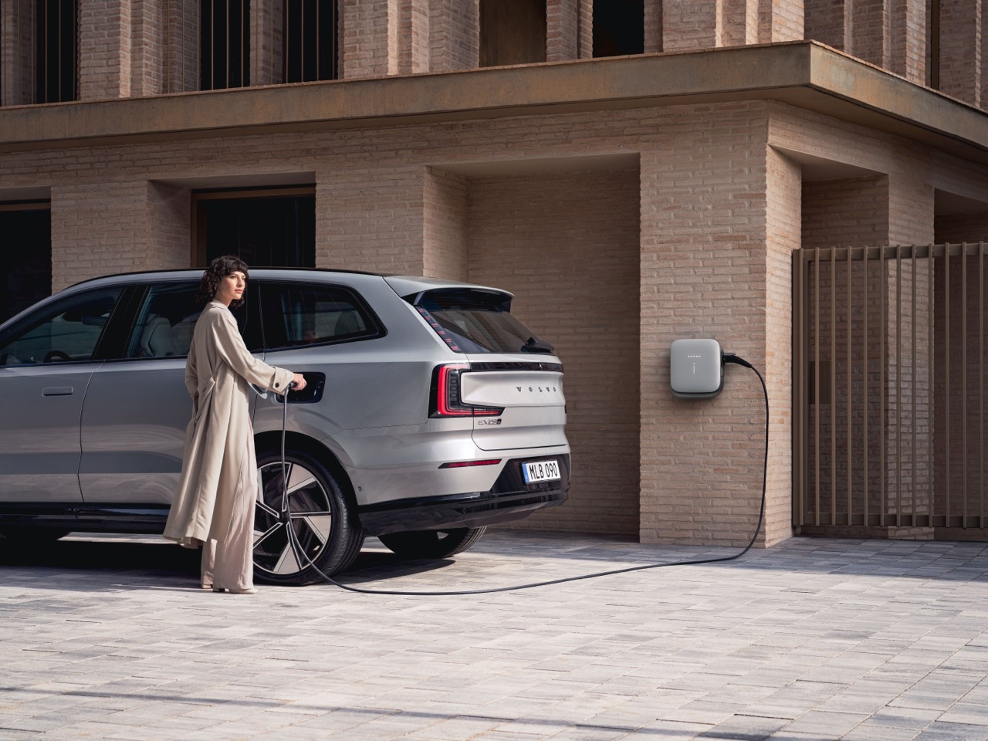 女士正在将充电线插入沃尔沃 EX90。