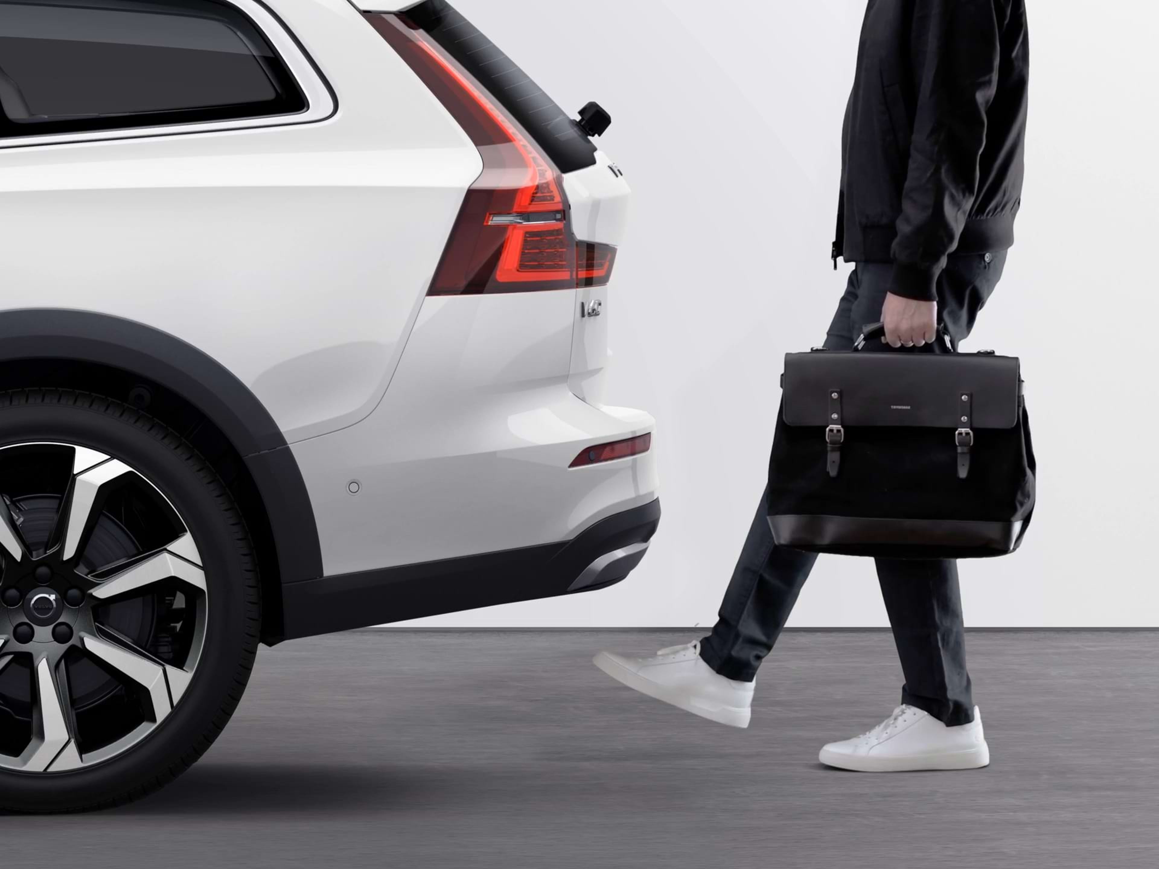 一名男士双手拿着东西,用脚扫过沃尔沃汽车保险杠的下方,便可打开电动尾门。