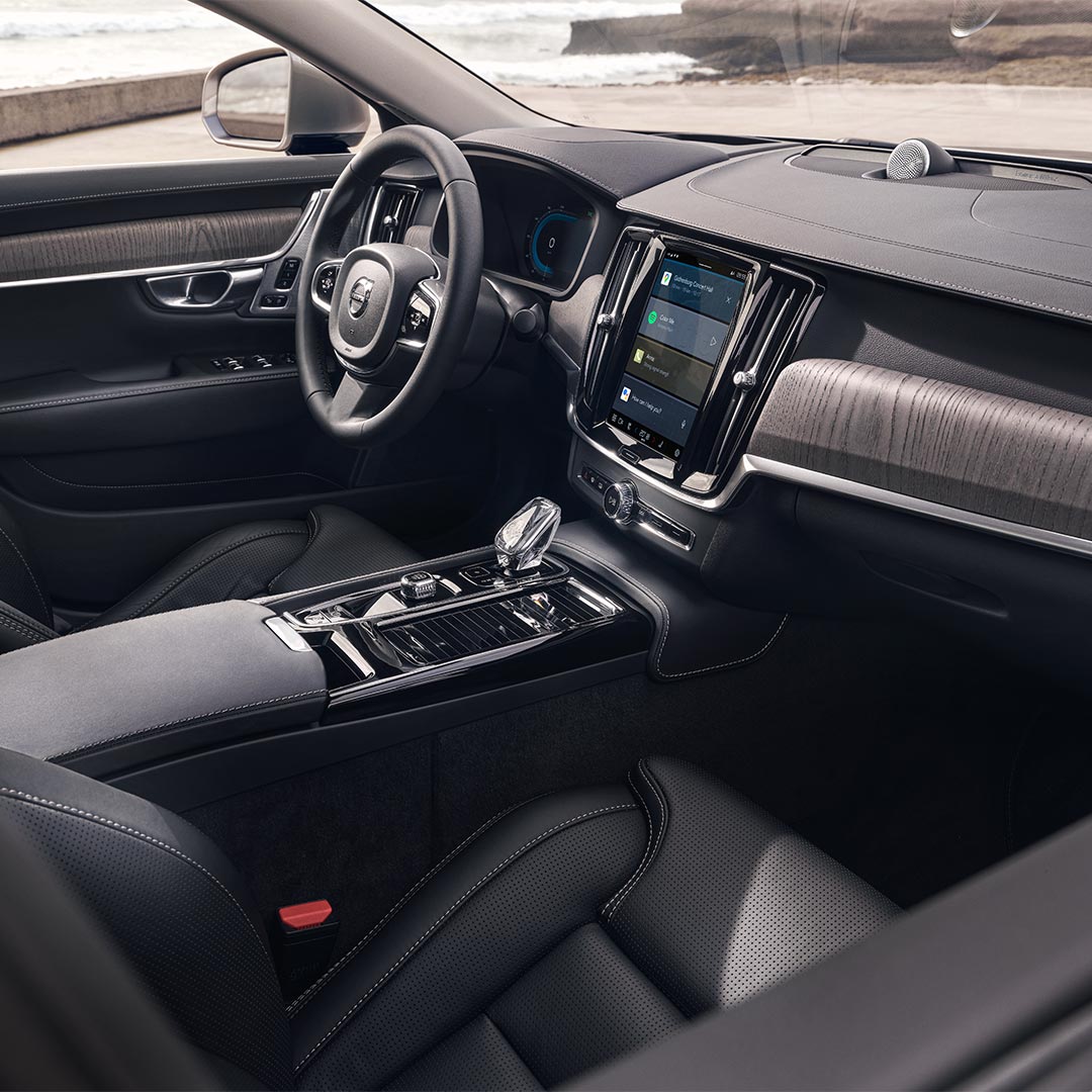 Volvo S90 插电式混合动力轿车内部驾驶员座椅、方向盘和中央显示屏视图。