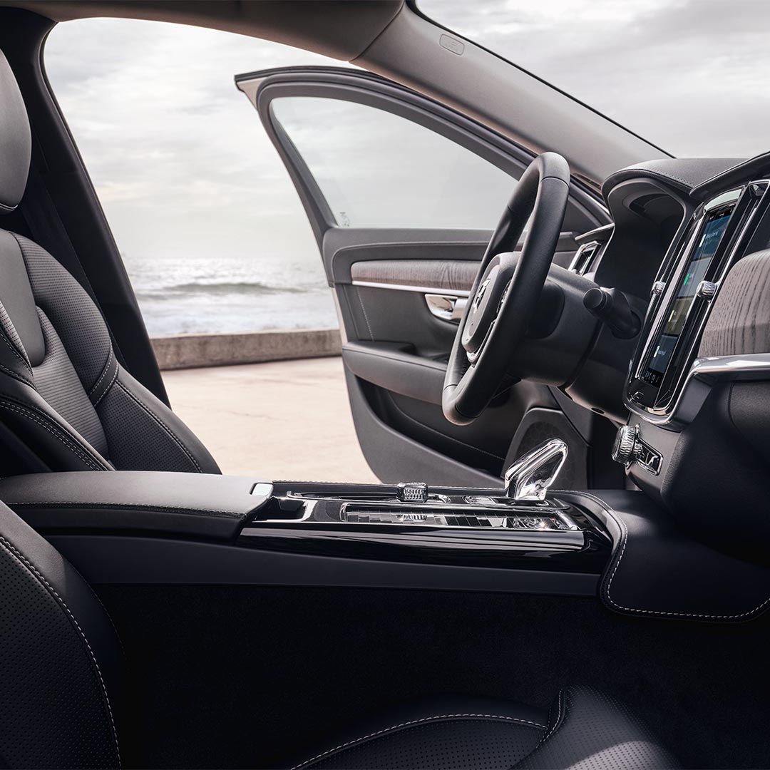 Volvo S90 插电式混合动力轿车内驾驶员座椅、方向盘、换挡杆和中央显示屏视图。