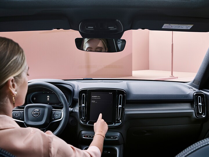 A woman inside a Volvo XC40 Recharge car, using the connectivity system