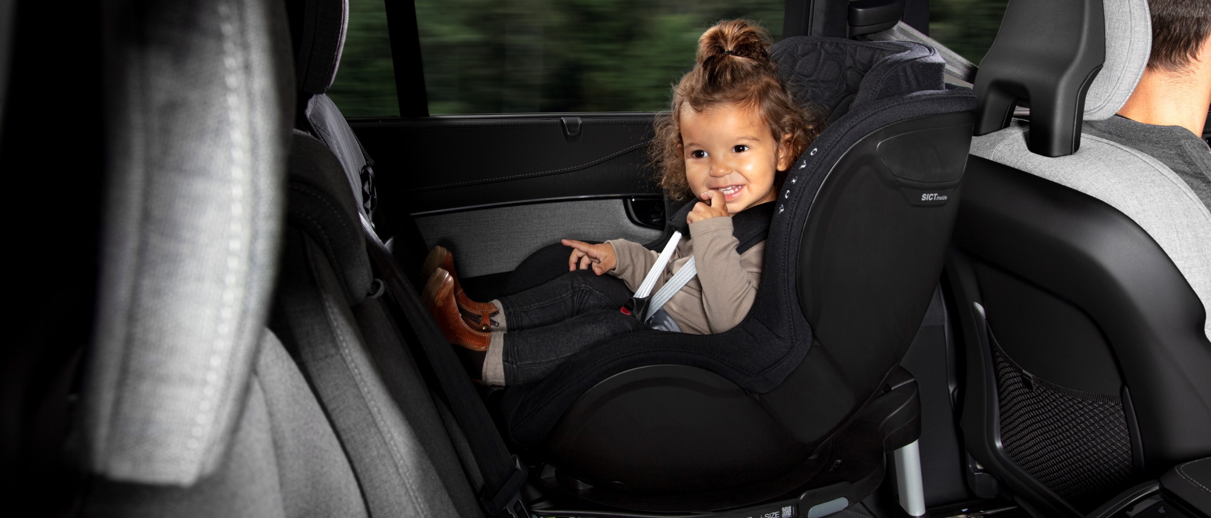 一名儿童在汽车座椅上微笑。