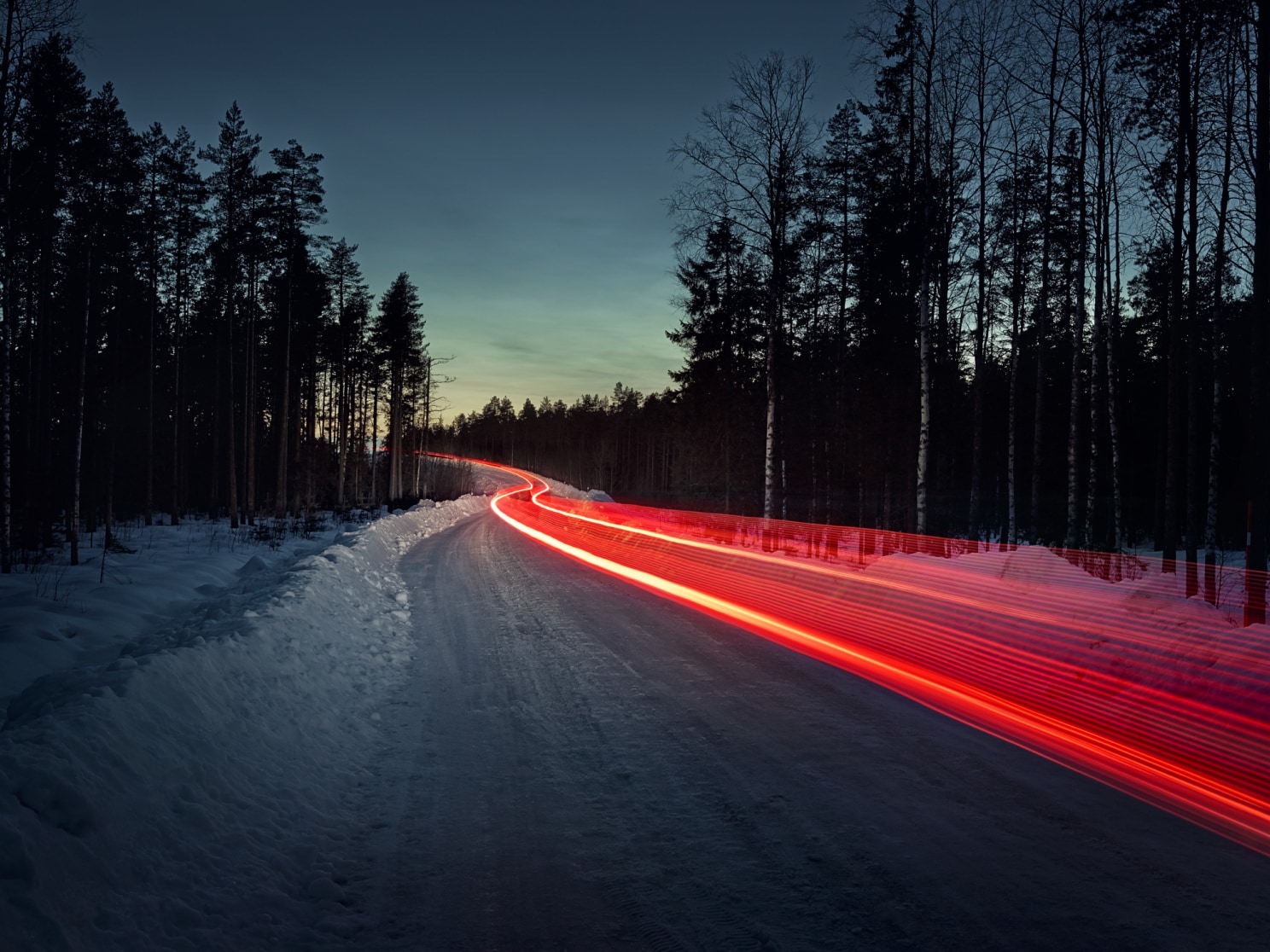 延时拍摄结冰道路上的一串红色尾灯。