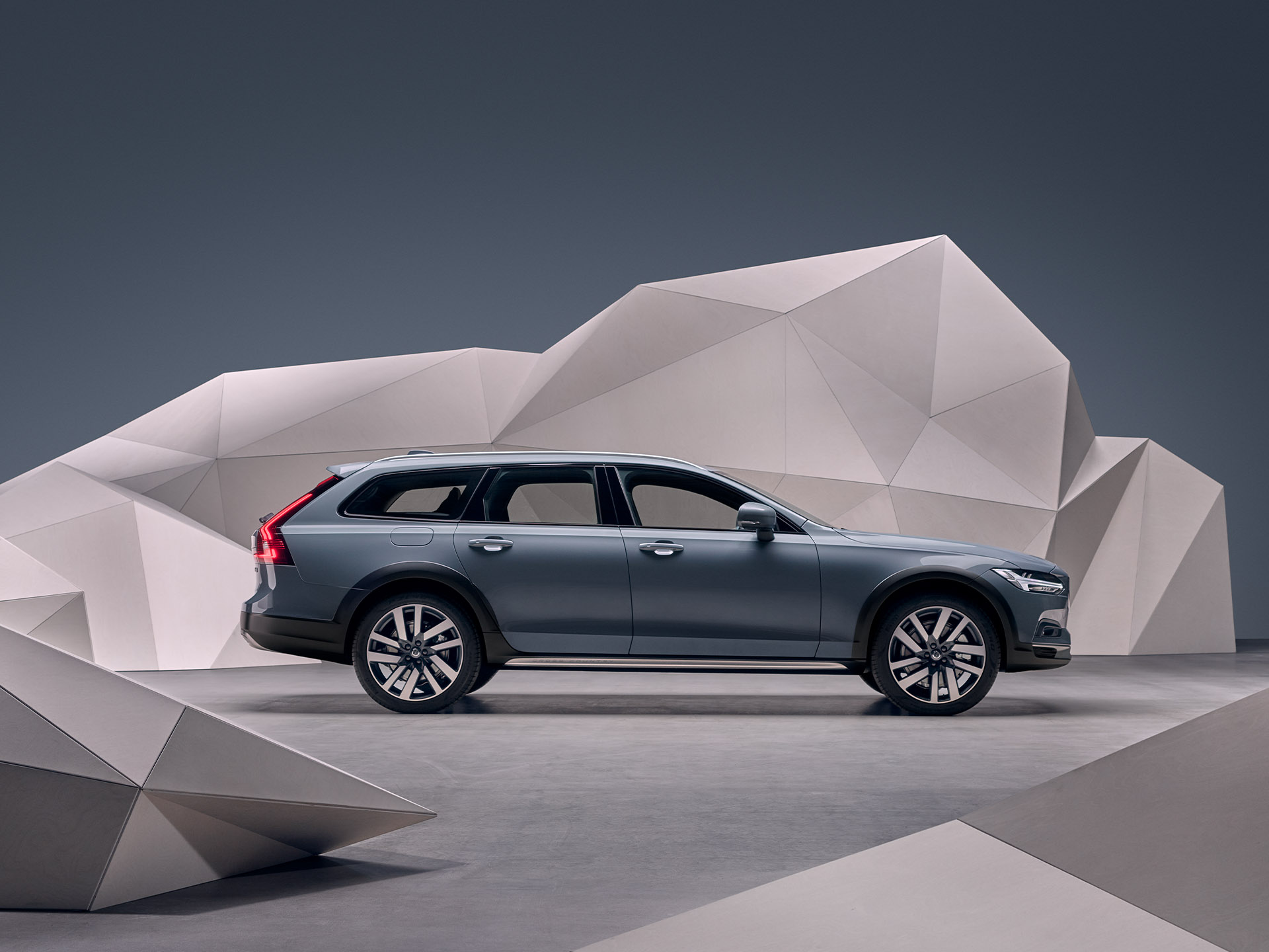 A mussel blue metallic Volvo Estate V90 standing in front of an artistic wall