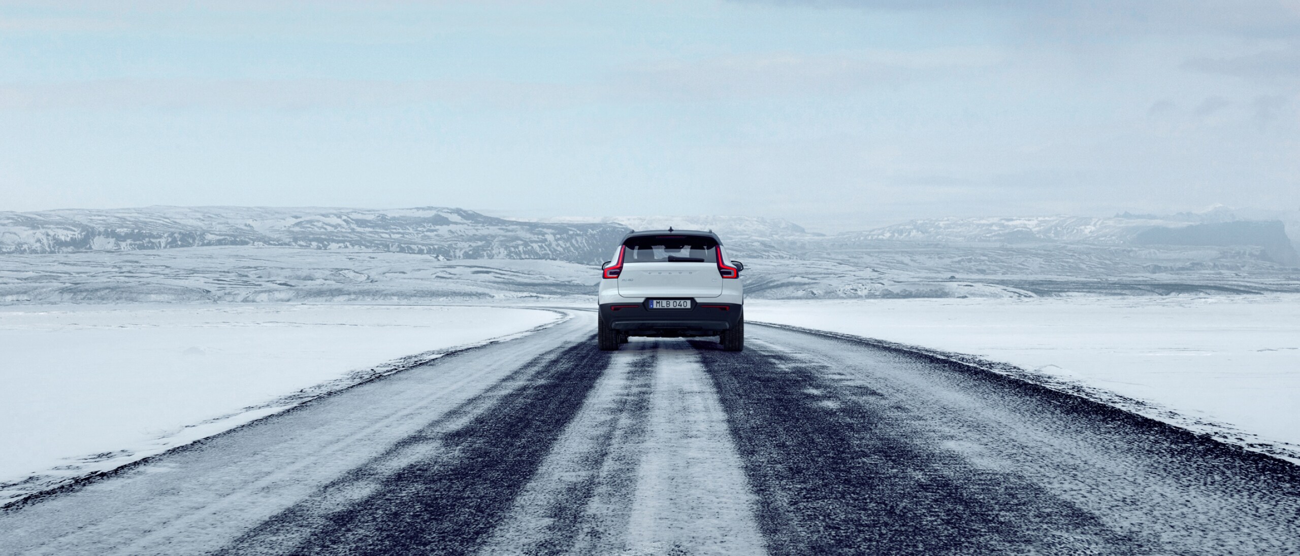 白色 VOLVO XC40 行驶在结冰路面的后视图。